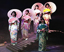 Five young Japanese women in traditional kimonos fans and parasols on a bridge
